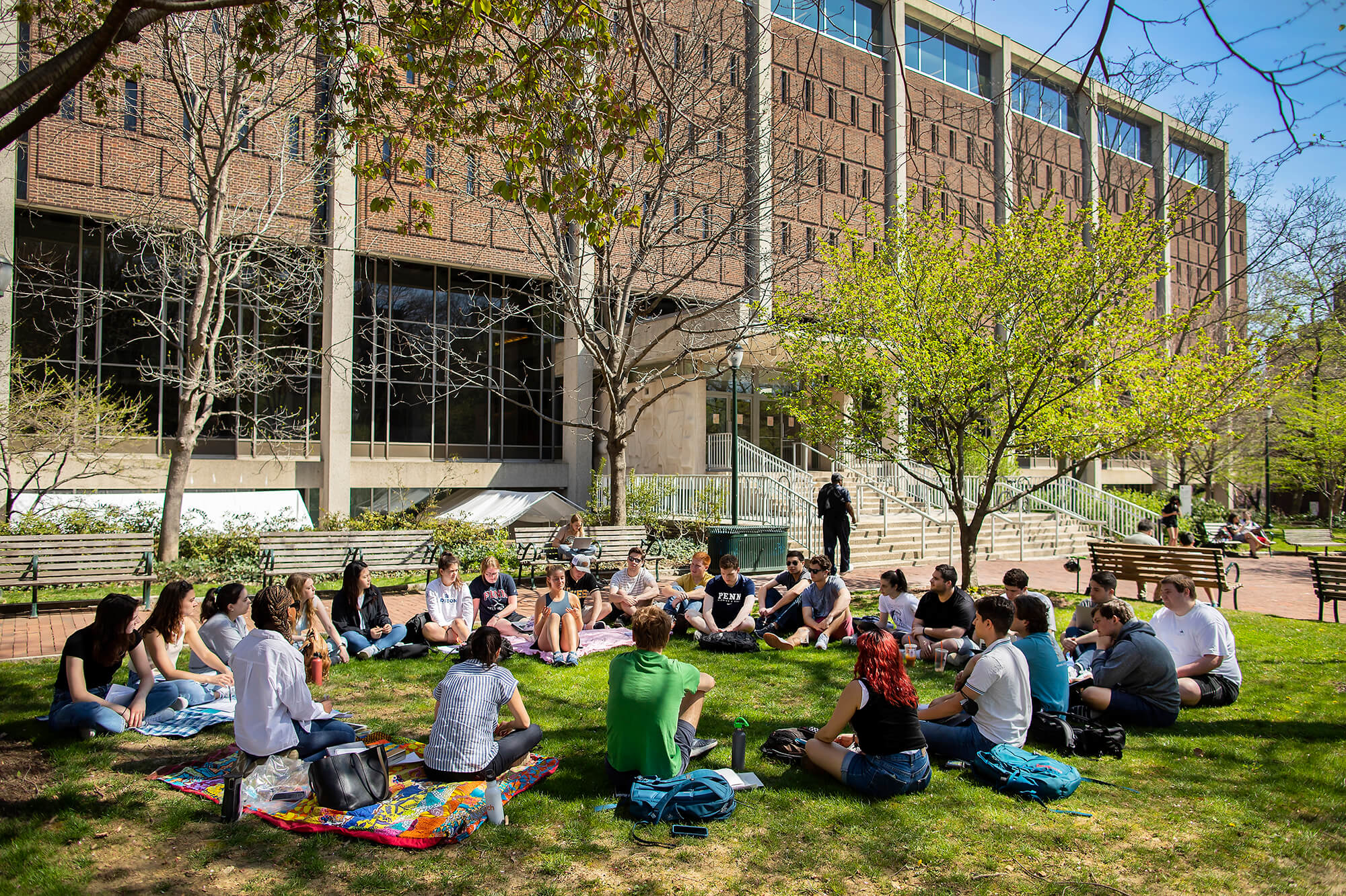 students sitting in grass on campus.